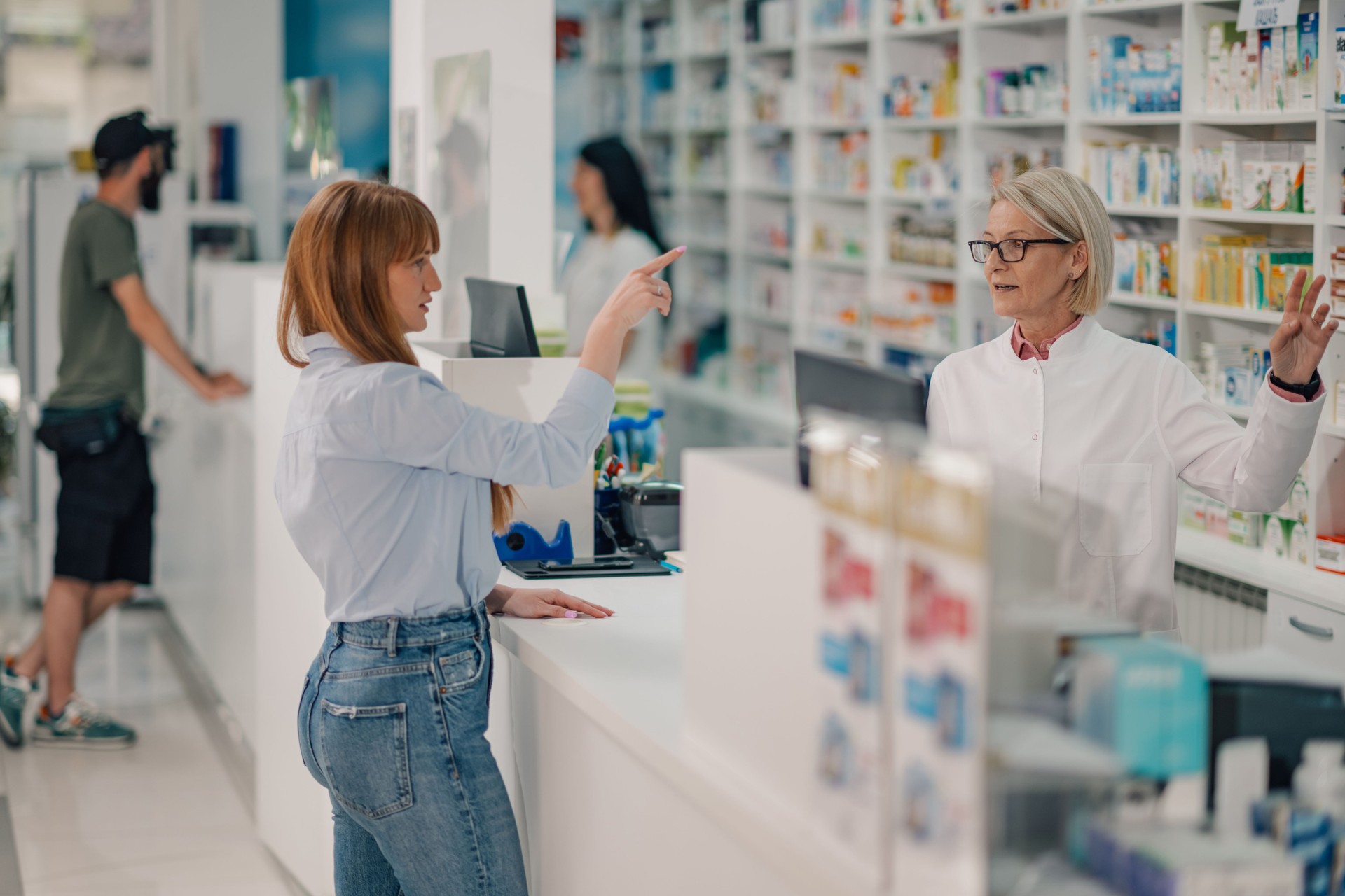 Customer choosing supplement at drugstore with senor pharmacist.