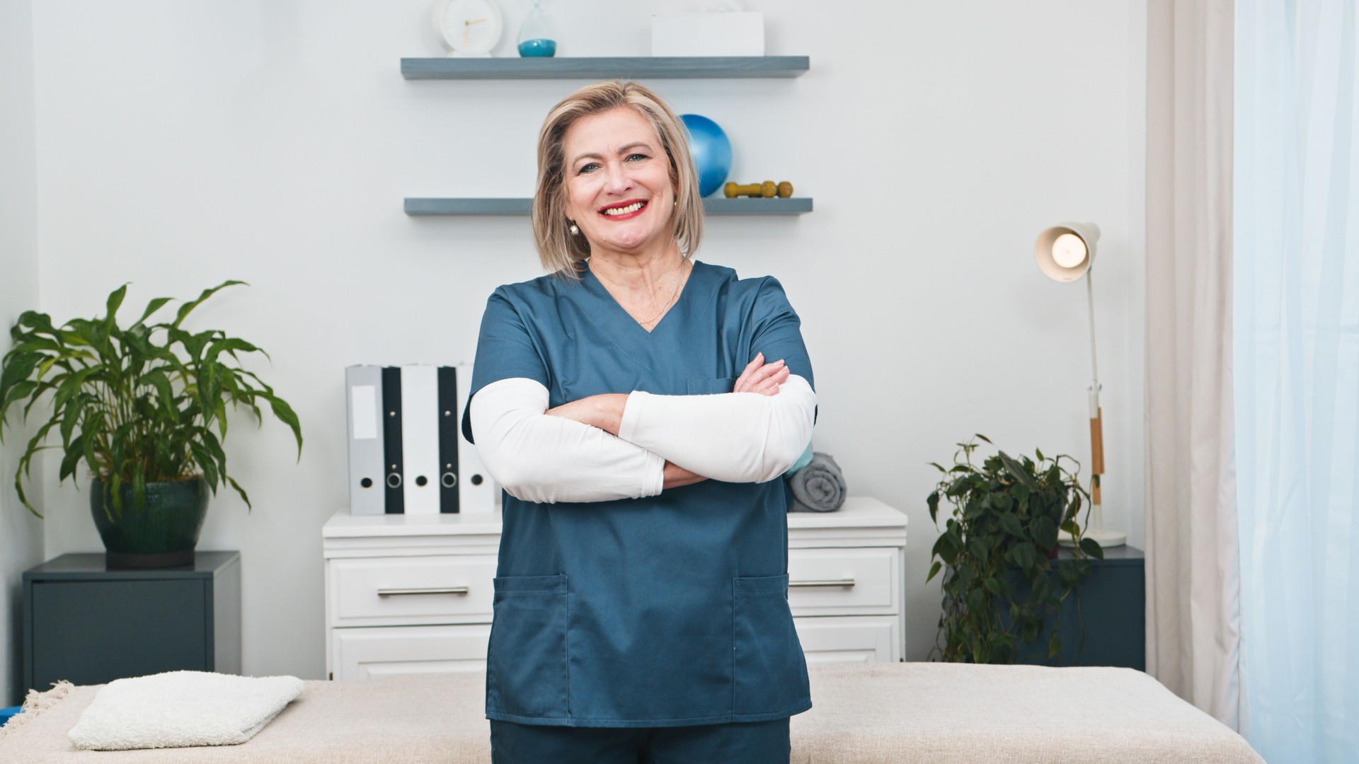 A Professional Senior Physiotherapist Smiles Confidently as a Dedicated Business Owner in Her Clean and Welcoming Small Practice,