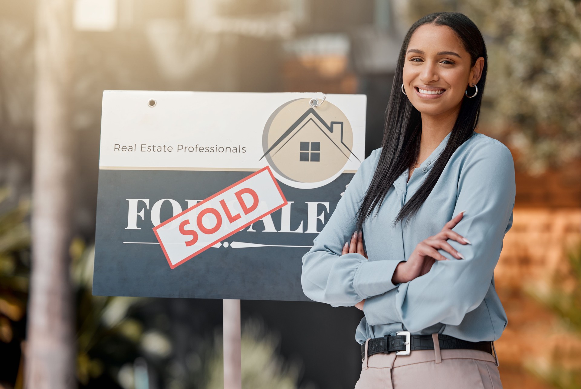 Shot of a real estate agent standing next to a sold sign outside