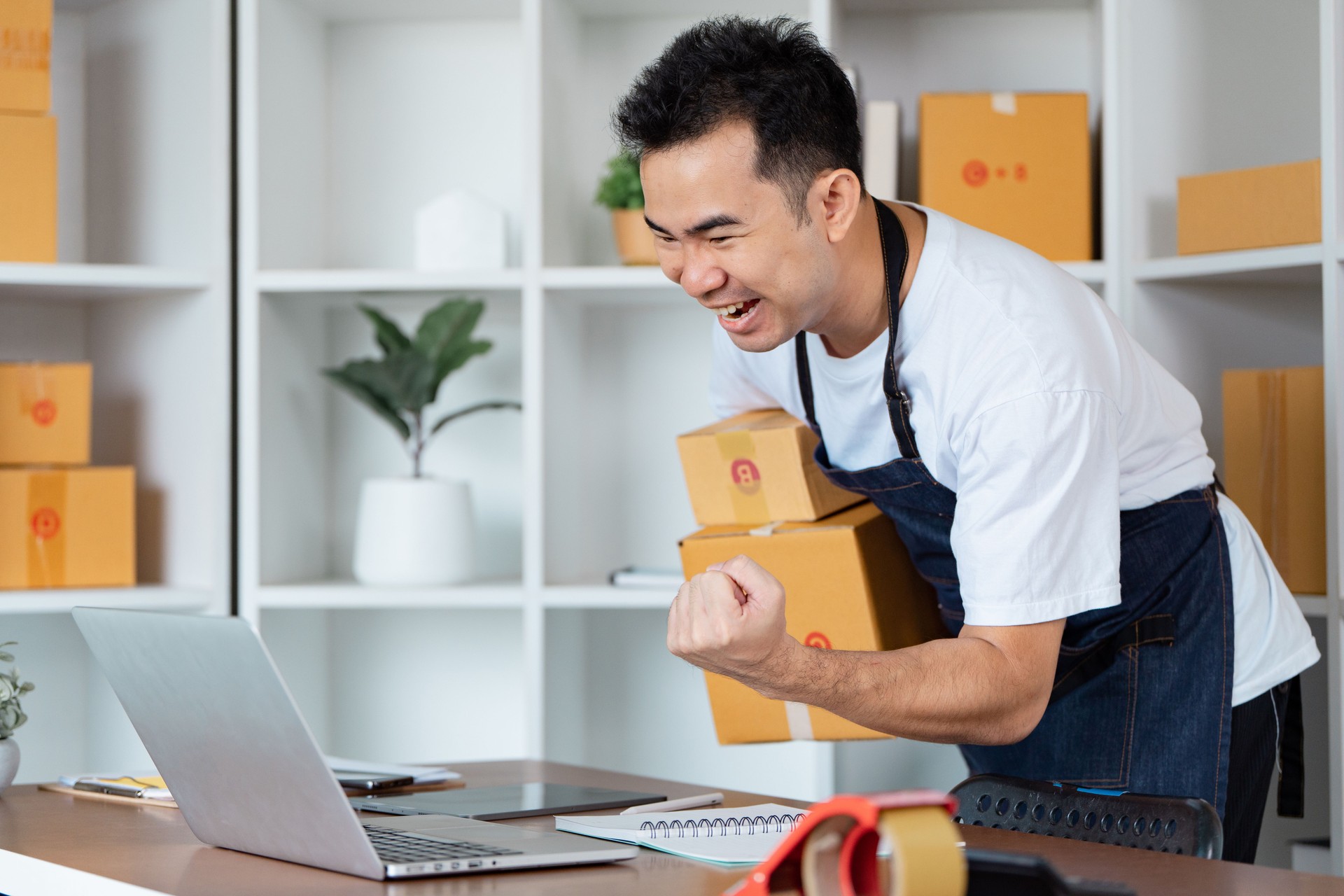 Excited small business owner celebrating successful online order fulfillment at home office