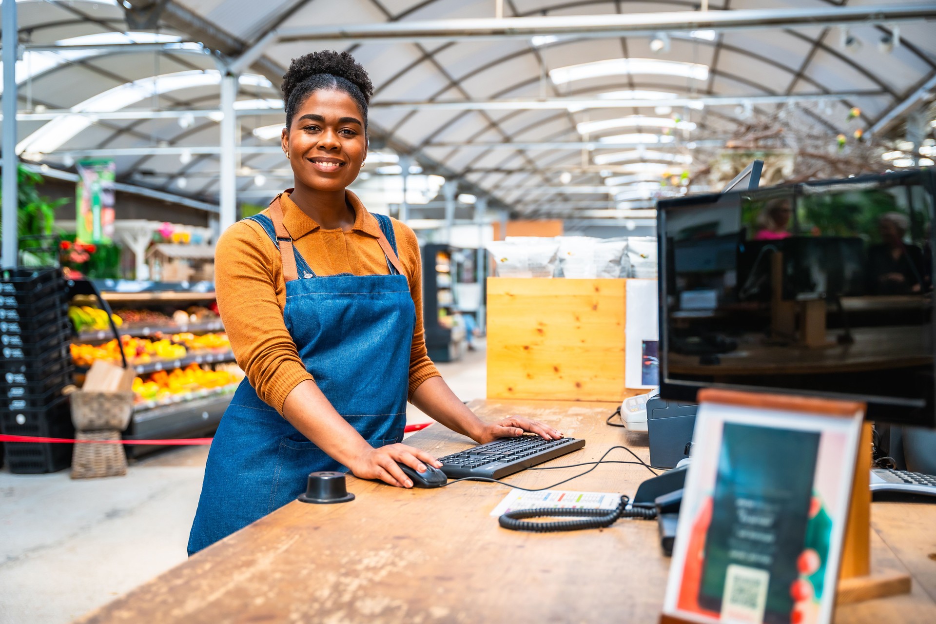 Young saleswoman working at checkout counter in supermarket