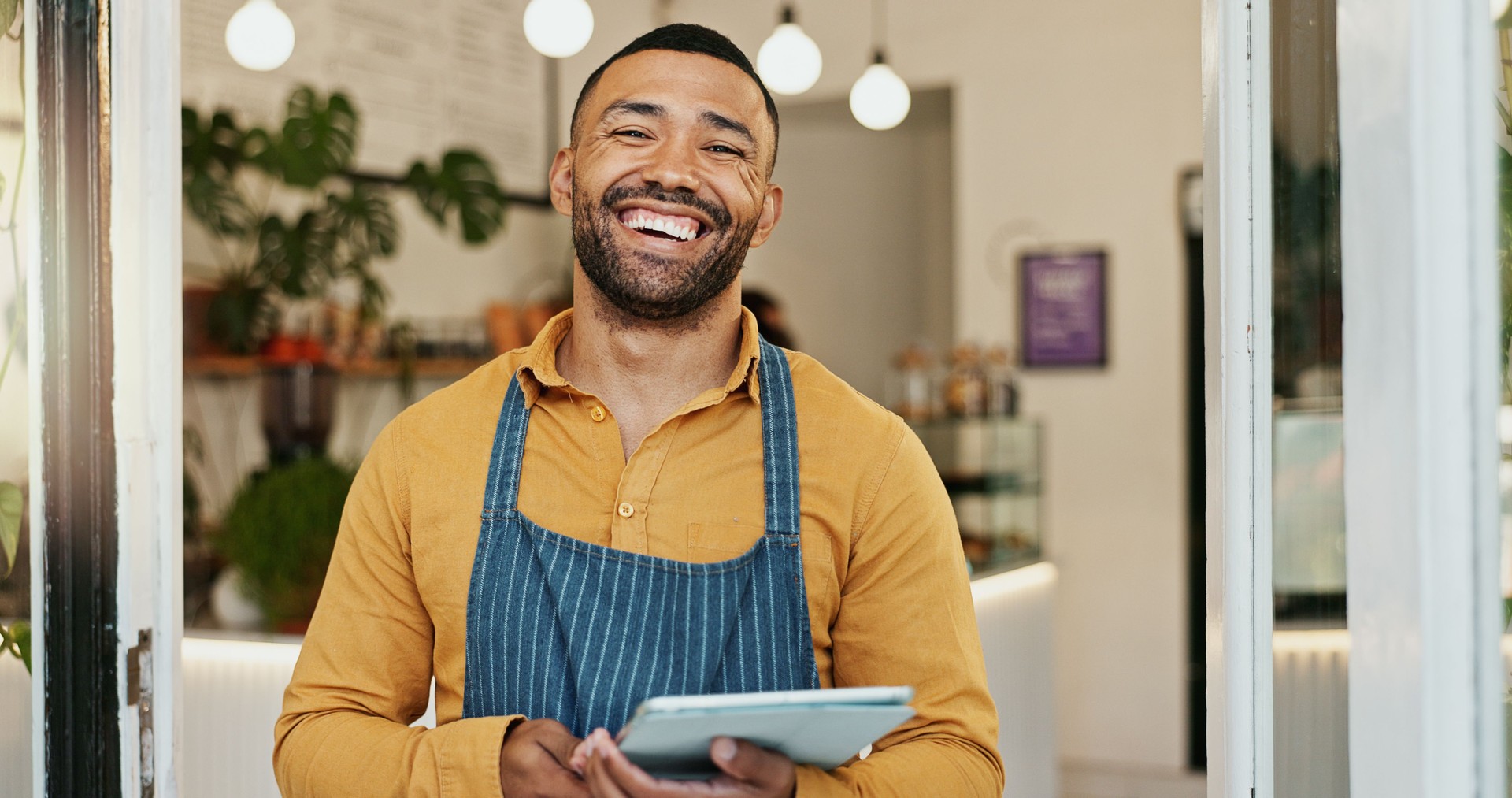 Small business, man and cafe portrait with tablet, happy employee and online inventory or website order. Hospitality, coffee shop and doorway for customer service, waiter and restaurant with internet
