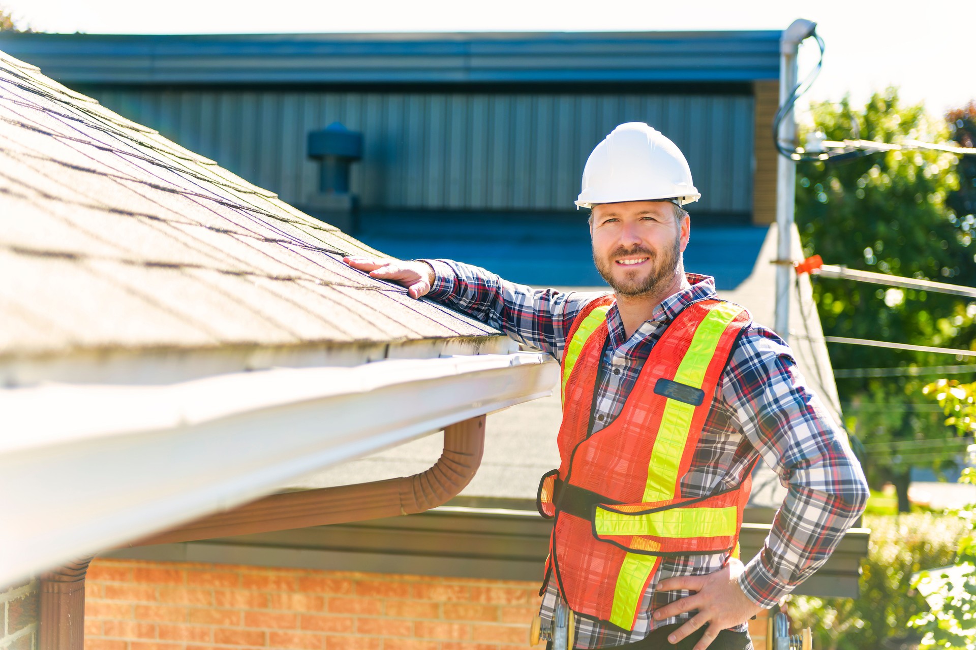 man with hard hat standing on steps inspecting house roof